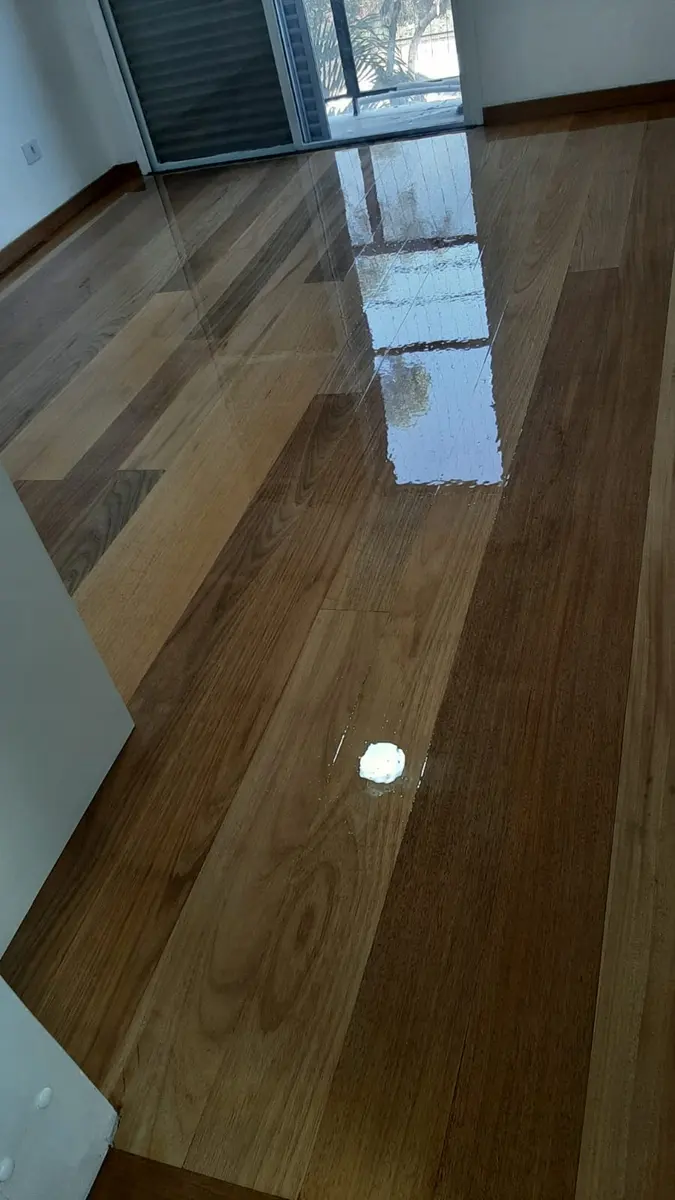 Assoalho de tábuas claras com rodapé e reflexo da porta, Aplicadora Embuarte
